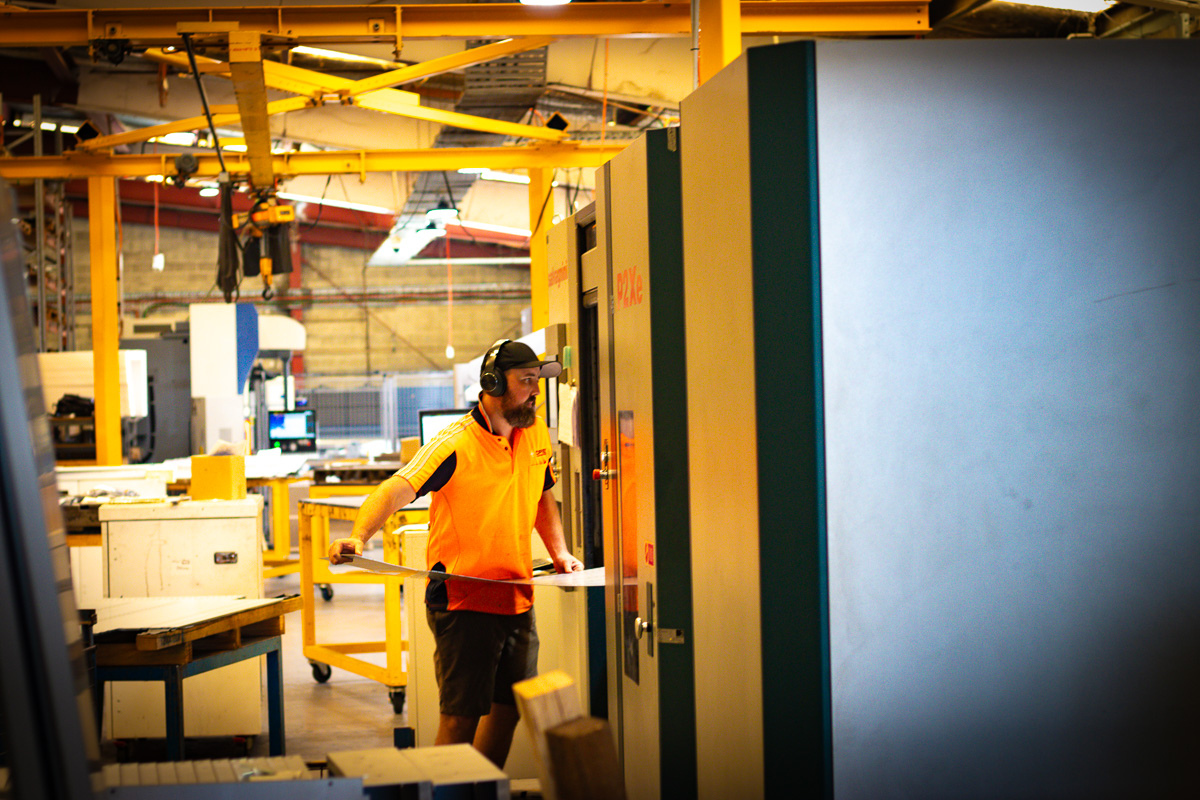 OPIE Manufacturing Group operator loading sheet metal into a CNC press brake in workshop